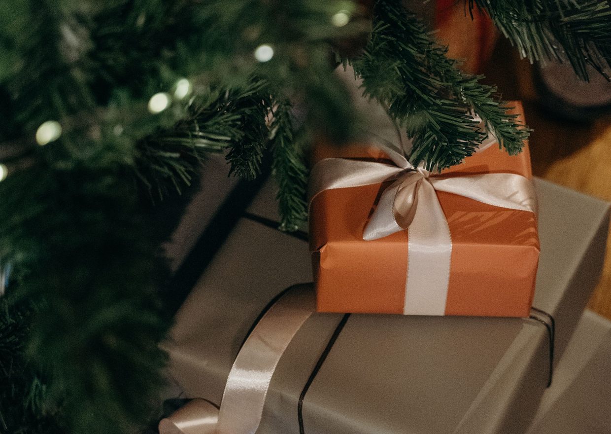 Wrapped gifts stacked under a lit Christmas tree